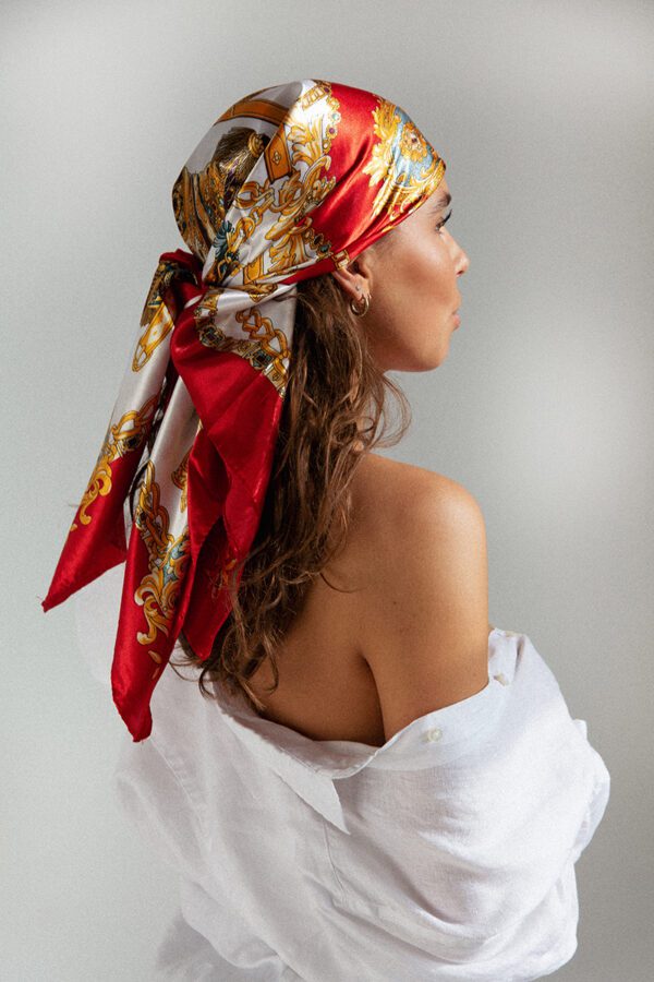 Foto van sjaal MÉLISE, een met vuurrode kleur geaccentueerde sjaal met elegant ketting-ontwerp gedragen als hoofdband.